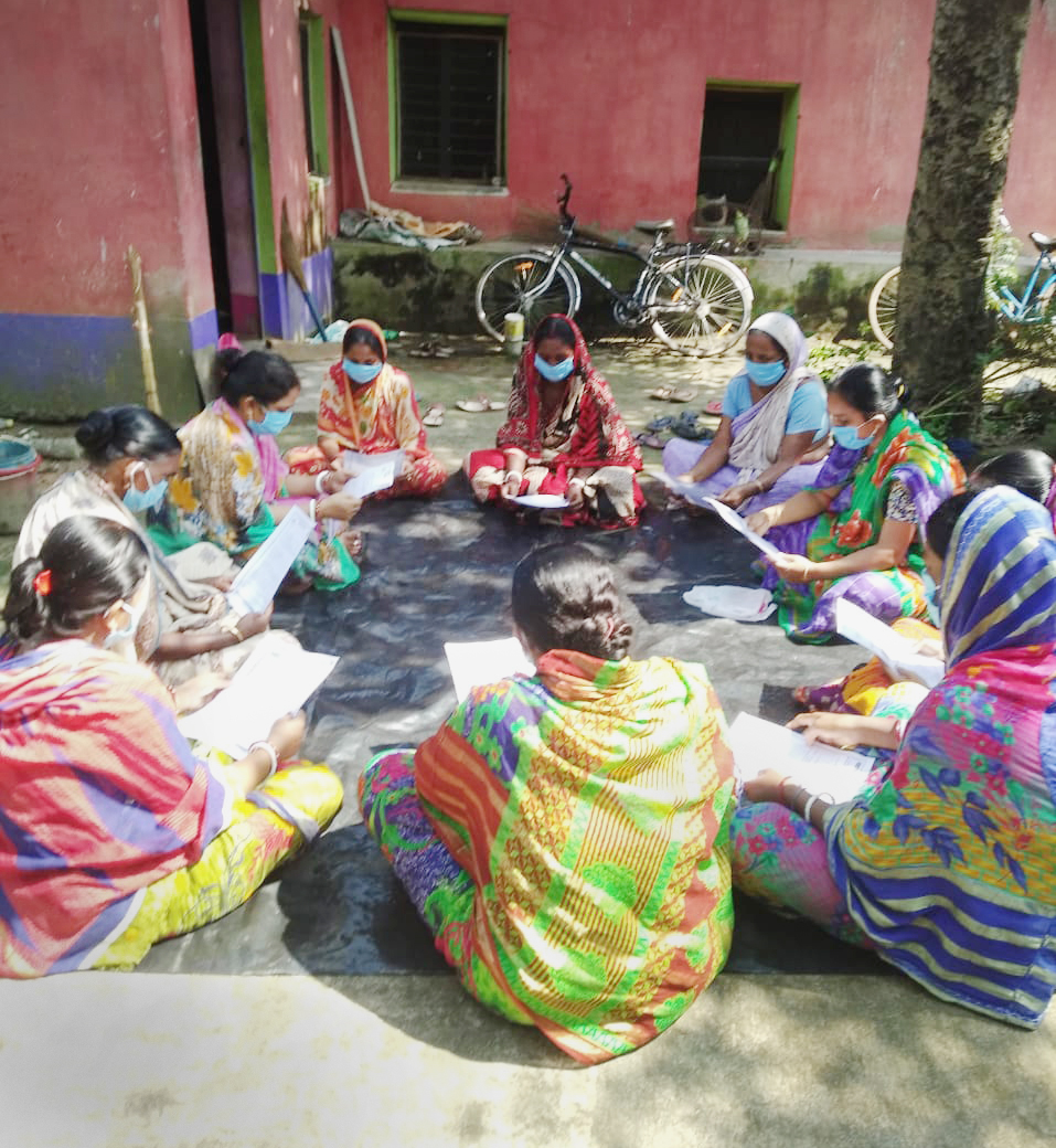 Women in India sitting in a circle with masks on